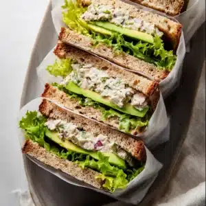 Close-up of fresh avocado tuna salad sandwich halves with lettuce and whole wheat bread