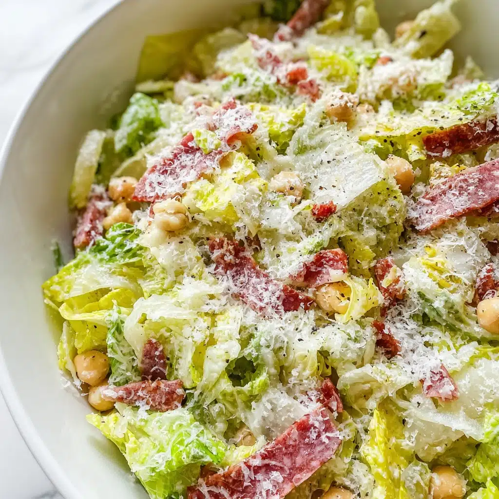 Copycat La Scala Chopped Salad mixed with lettuce, salami, chickpeas, and mozzarella, topped with cheese and black pepper in a white bowl.