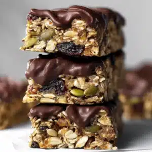 Stacked healthy flapjack bars with dark chocolate drizzle and seeds