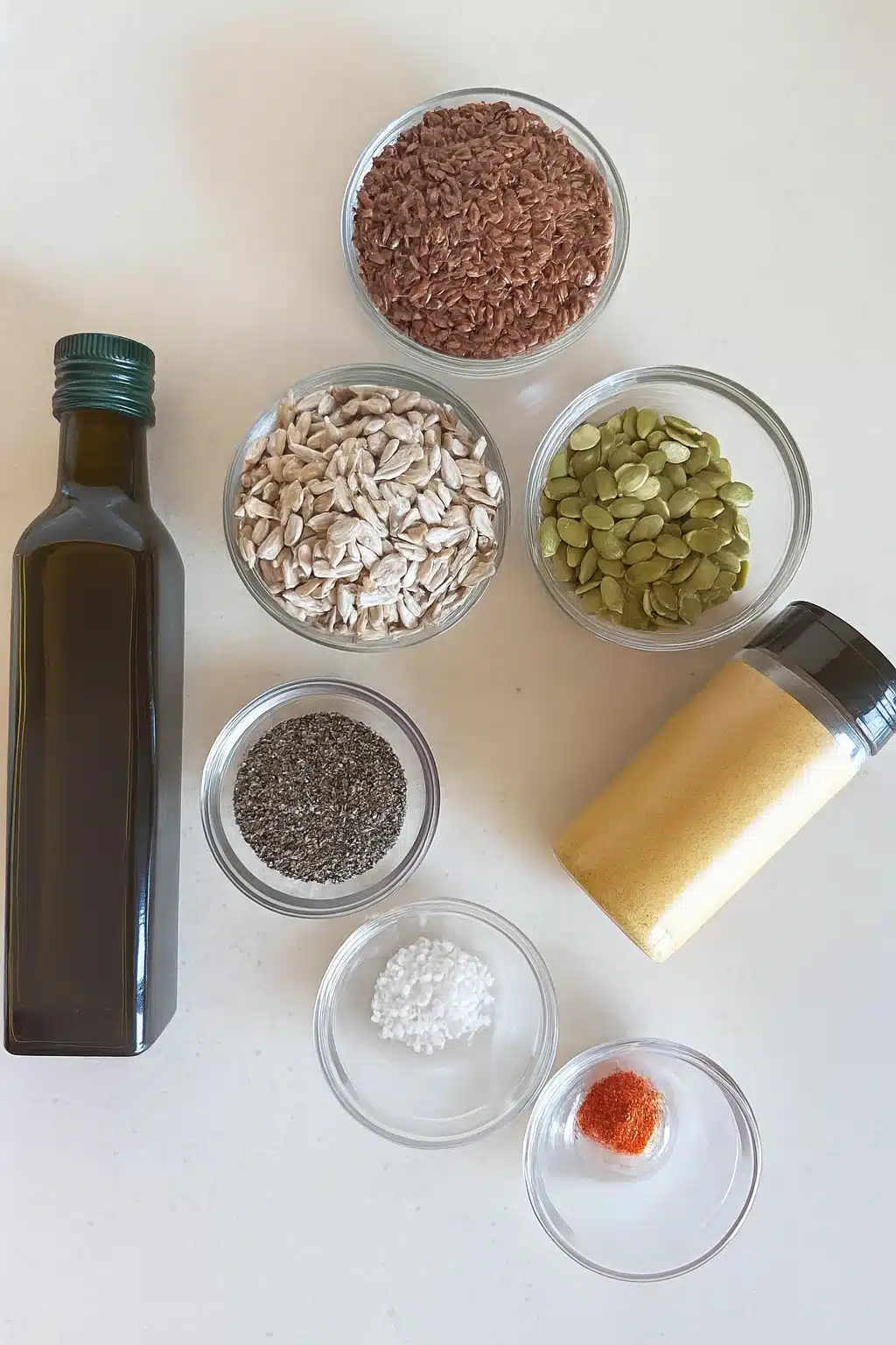 Flat lay of Bariatric Seed Trick ingredients like seeds, nutritional yeast, and olive oil on a clean white counter.