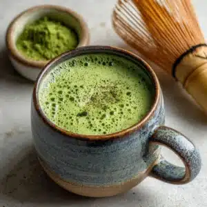 Rustic ceramic cup of frothy matcha tea with bamboo whisk and matcha powder bowl for matcha recipe for weight loss