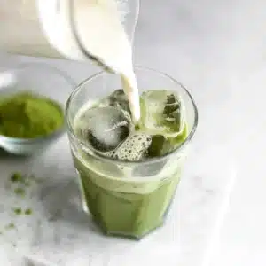 Low Calorie Iced Matcha Latte being poured with almond milk