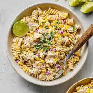 Street Corn Pasta Salad with rotini, corn, chicken, and lime in white bowl