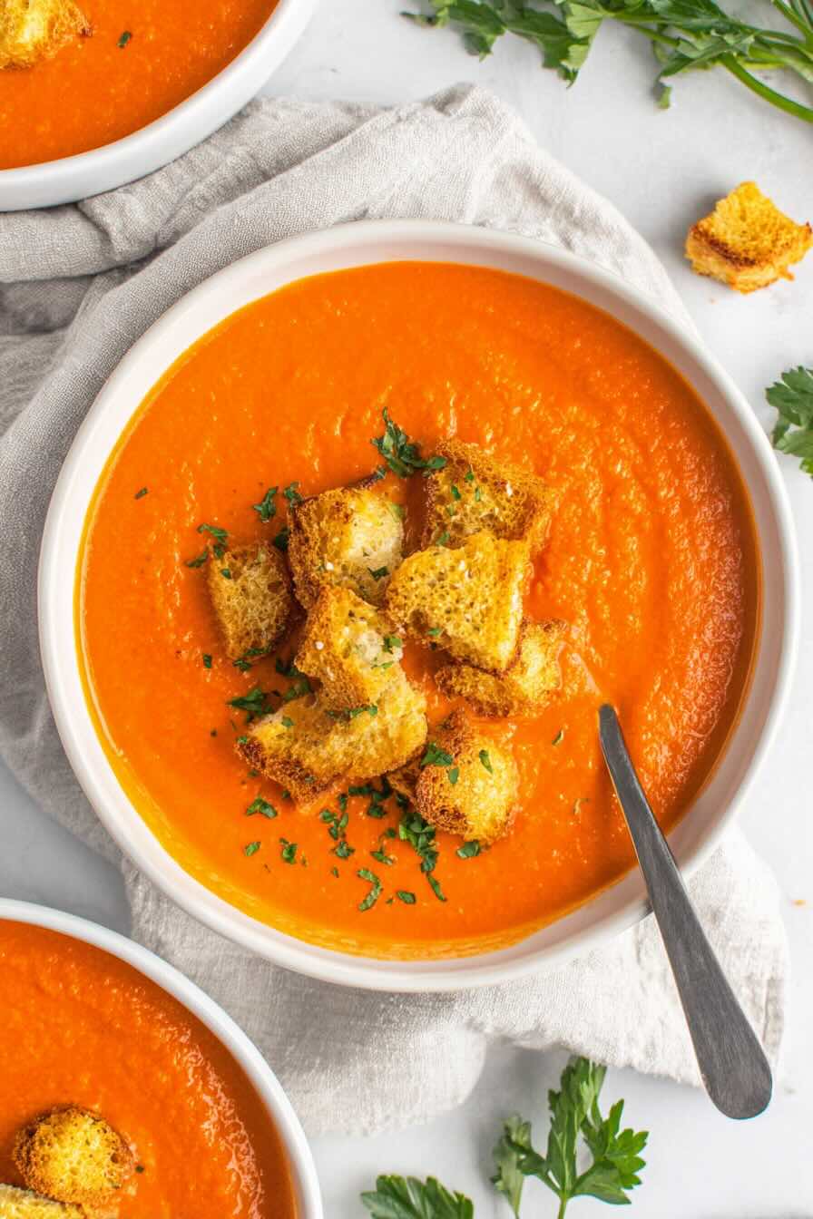 Creamy vegan tomato soup with croutons and parsley garnish