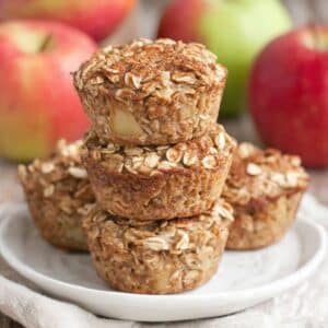 Apple cinnamon baked oatmeal cups stacked with apples in background