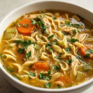 Vegan chicken noodle soup with carrots, celery, and pasta in a white bowl