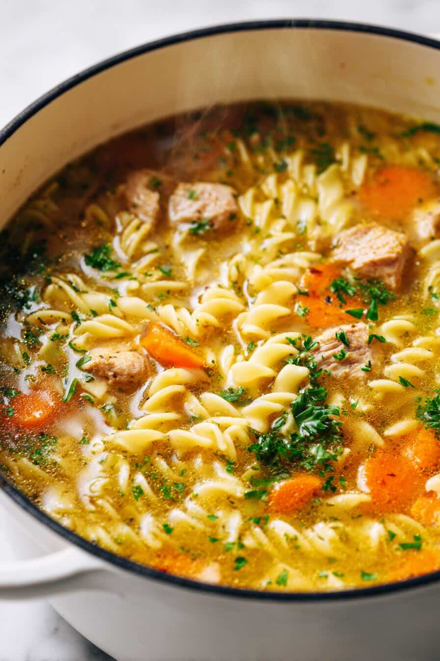 Steaming pot of vegan chicken noodle soup with vegetables and pasta