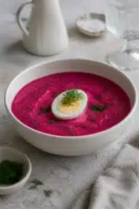 Bowl of cold beet soup topped with hard-boiled egg and fresh dill